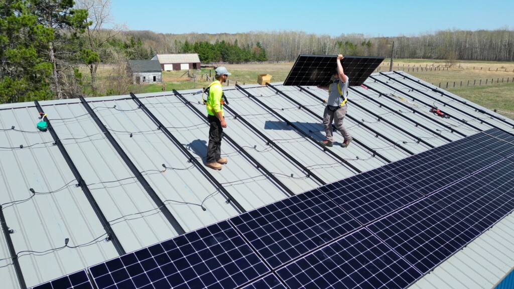 Skilled technicians installing solar panels on a metal roof, showcasing Wolf River Construction's expertise in renewable energy solutions.