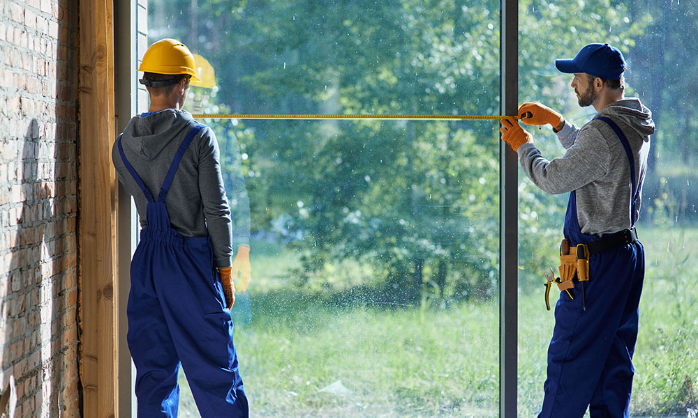 Construction workers measuring for window installation by Wolf River Construction, ensuring precision and energy efficiency.